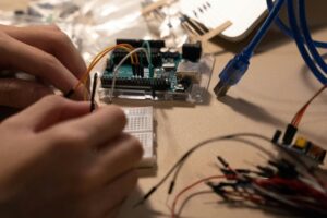 Close-up of hands assembling electronic components on a breadboard with wires.