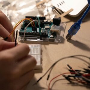 Close-up of hands assembling electronic components on a breadboard with wires.